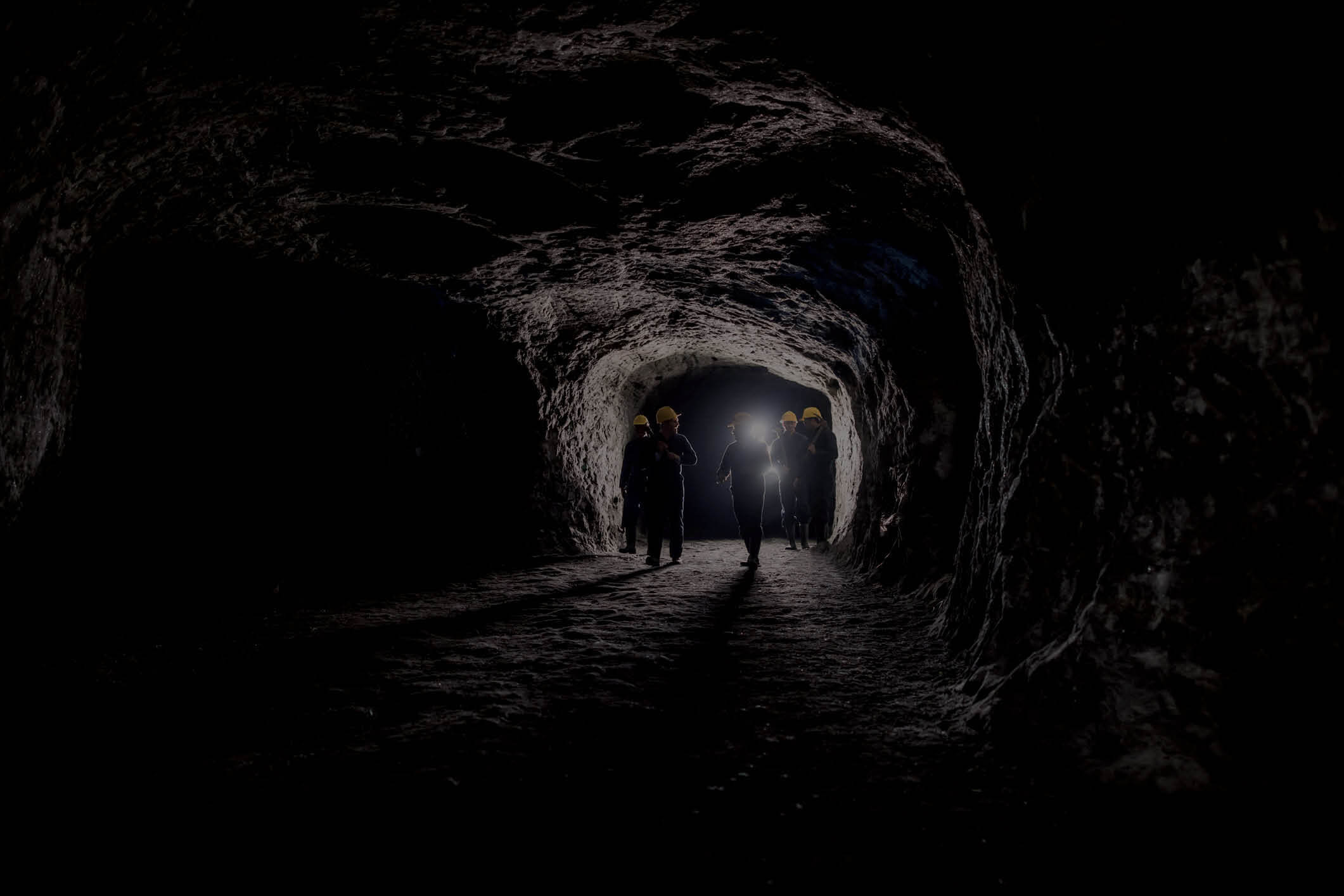 A group equipped with lights and safety gear in an underground mine